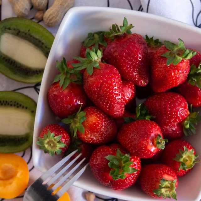 A vibrant flat lay of fresh strawberries and kiwi slices in a ceramic bowl, perfect for food photography.